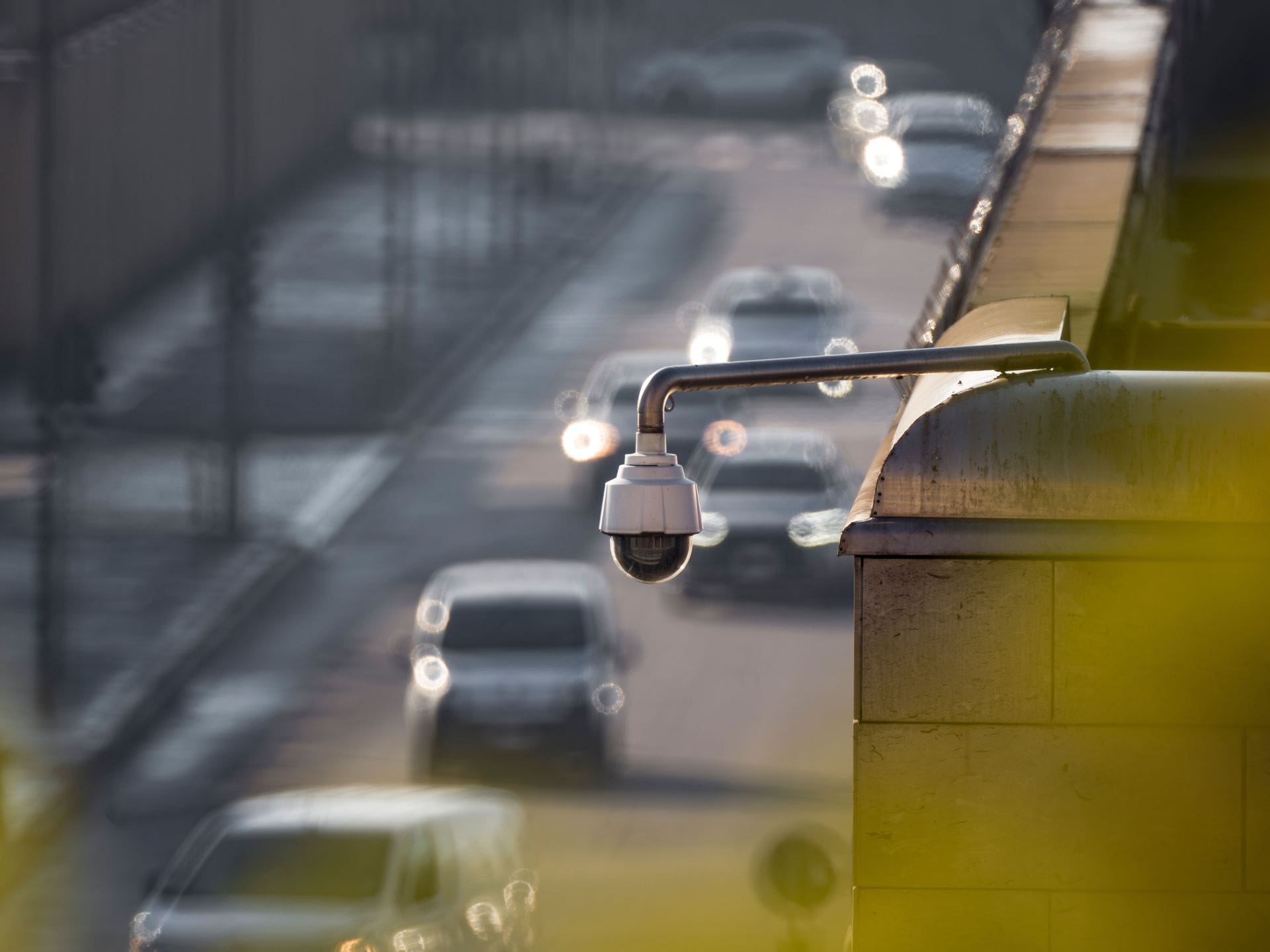 Security camera mounted on a bridge overlooking blurred traffic on a highway